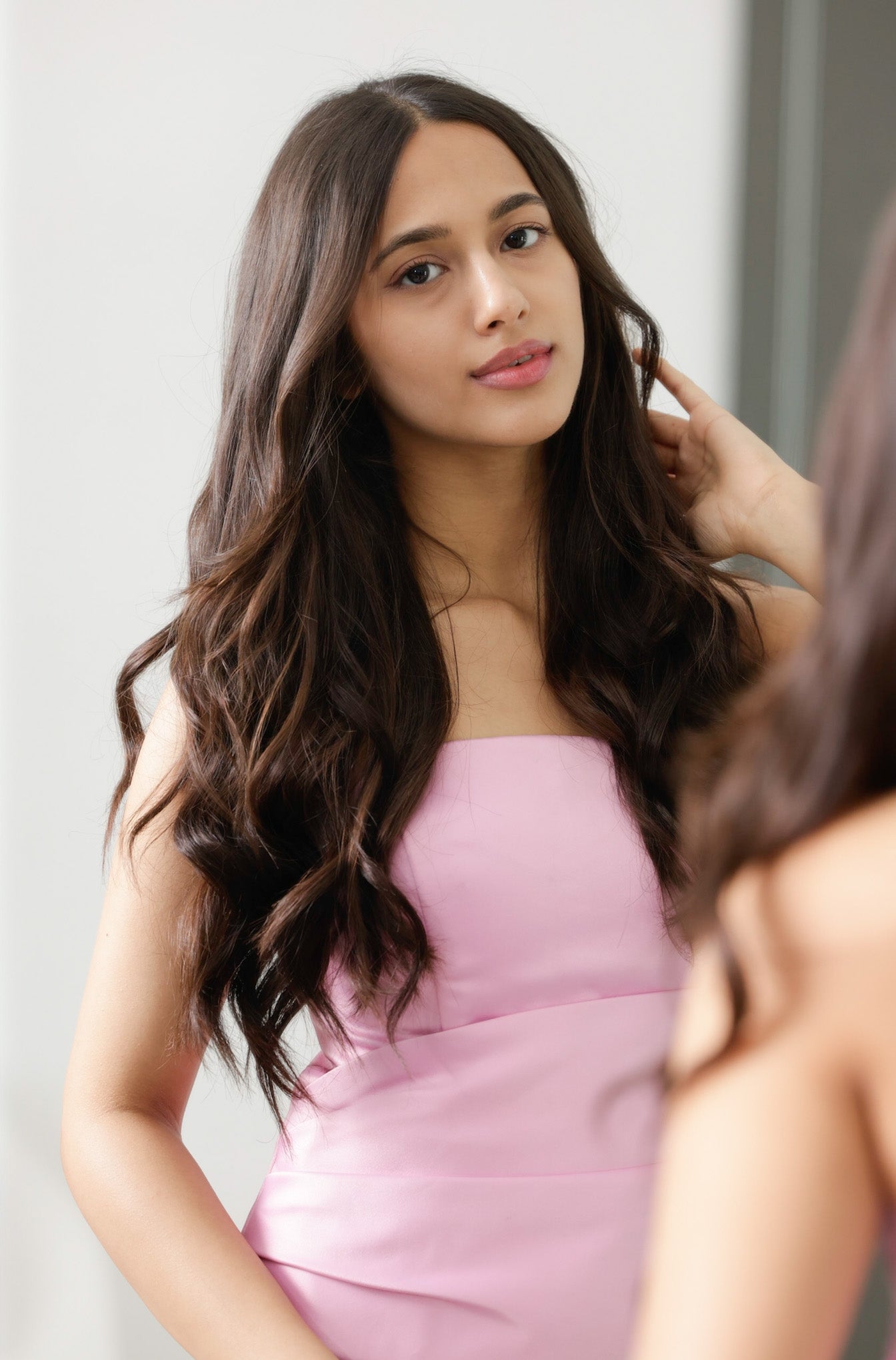A woman with long, wavy hair posing and looking at the camera.