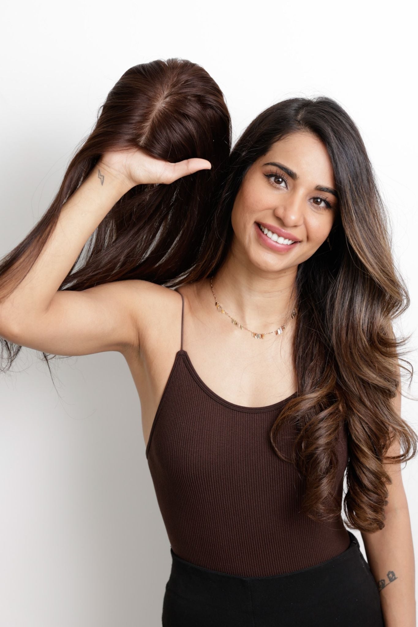 Woman holding a hairpiece with realistic scalp texture, smiling at the camera