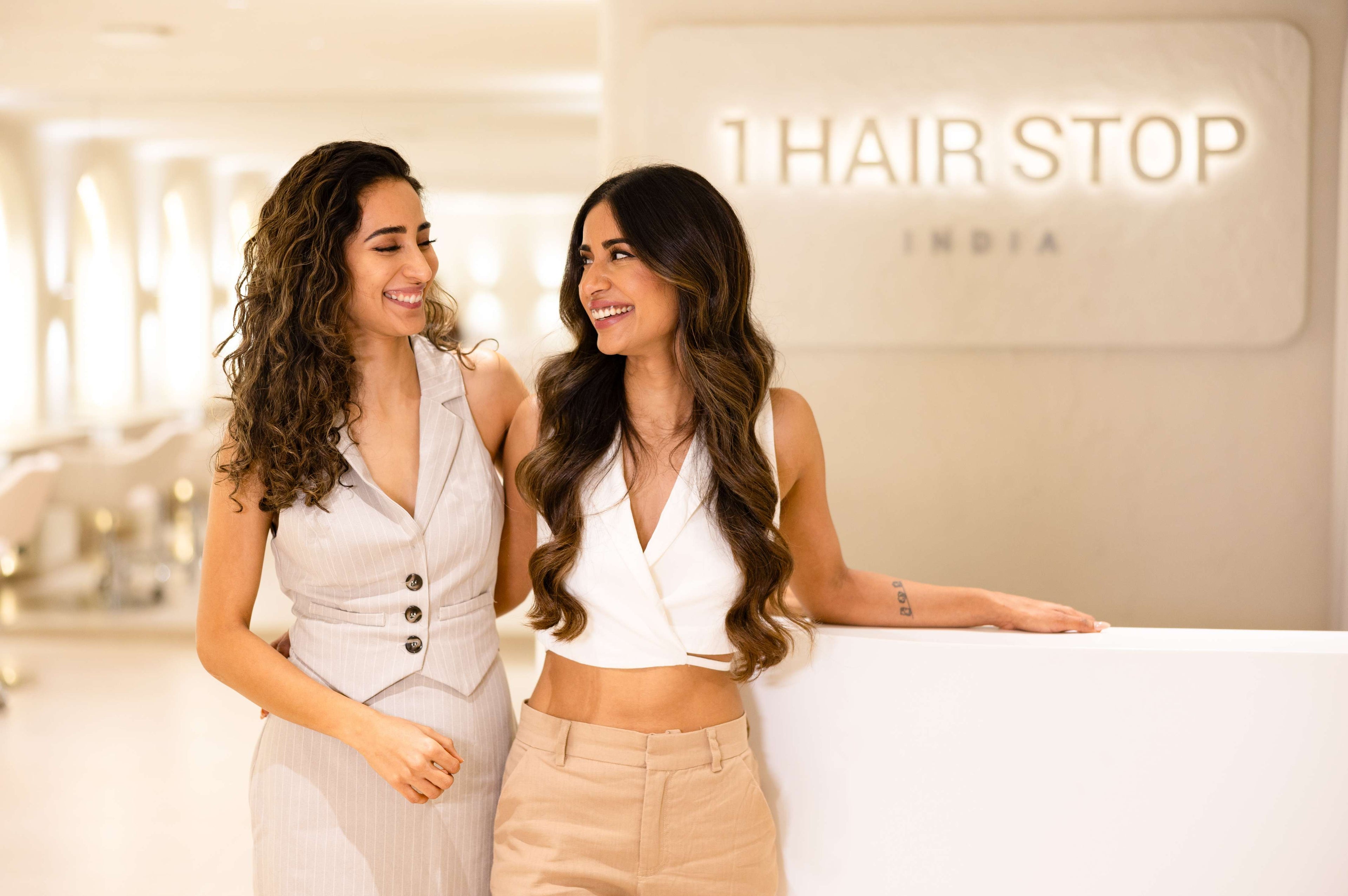Two women smiling and chatting in front of a salon sign, enjoying their time together