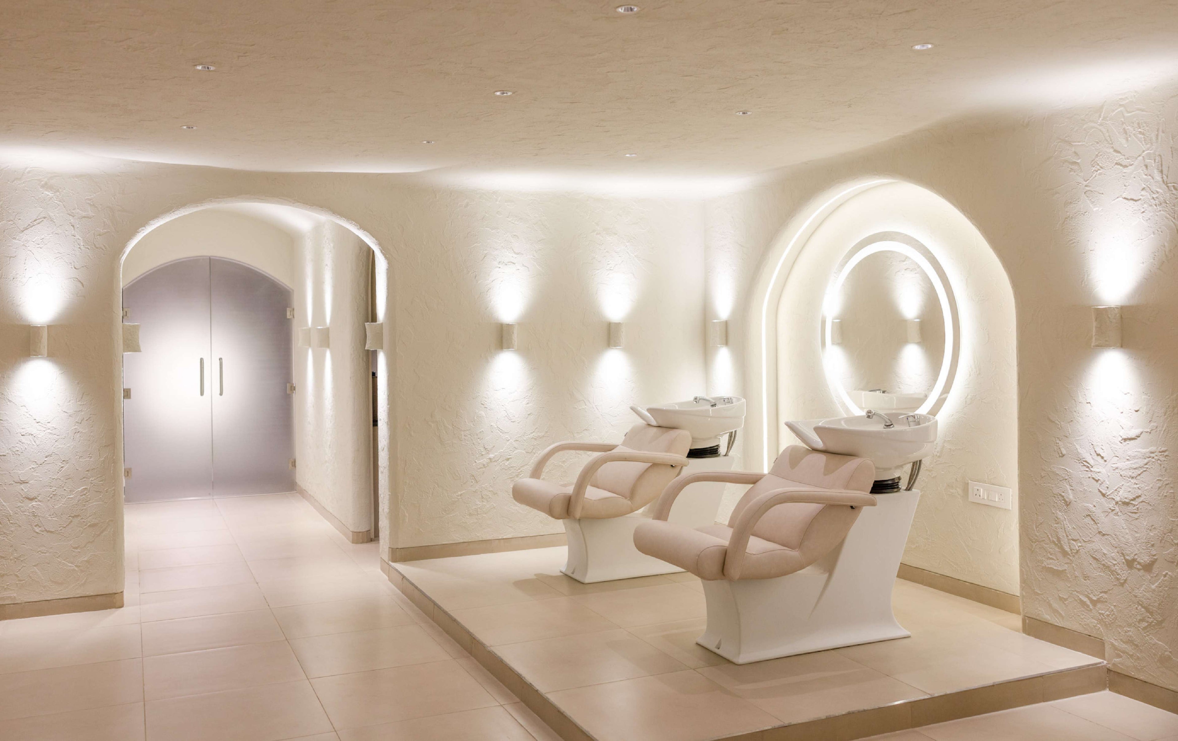 A modern hair salon interior with two white salon chairs and washing stations.