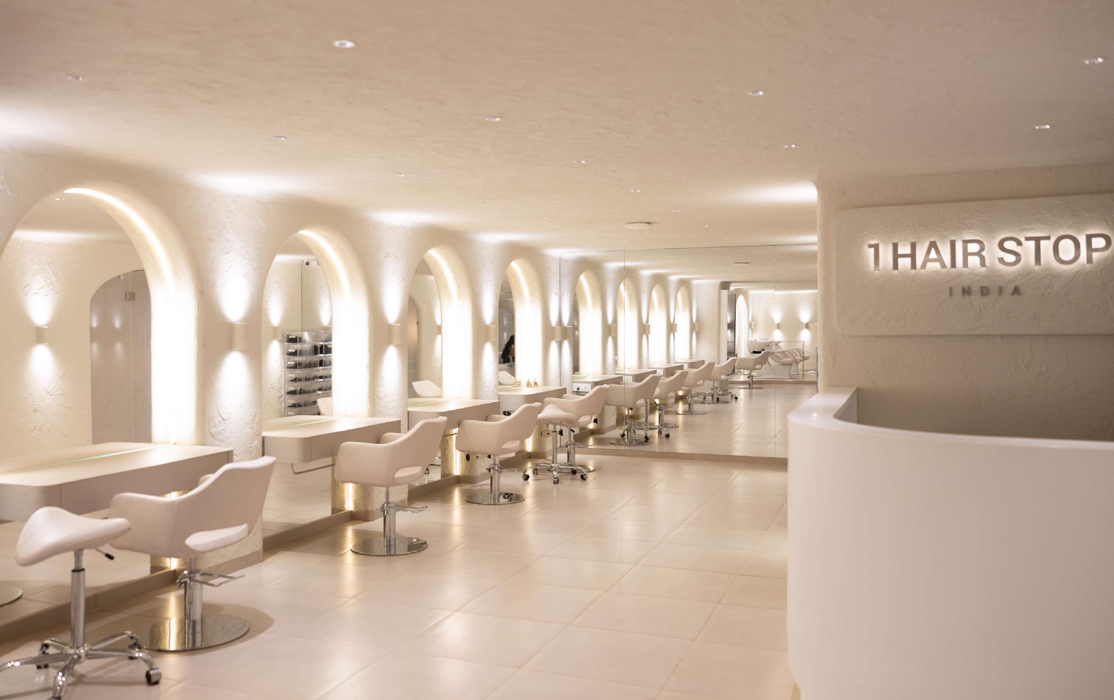 Modern hair salon with white chairs and arched mirrors.