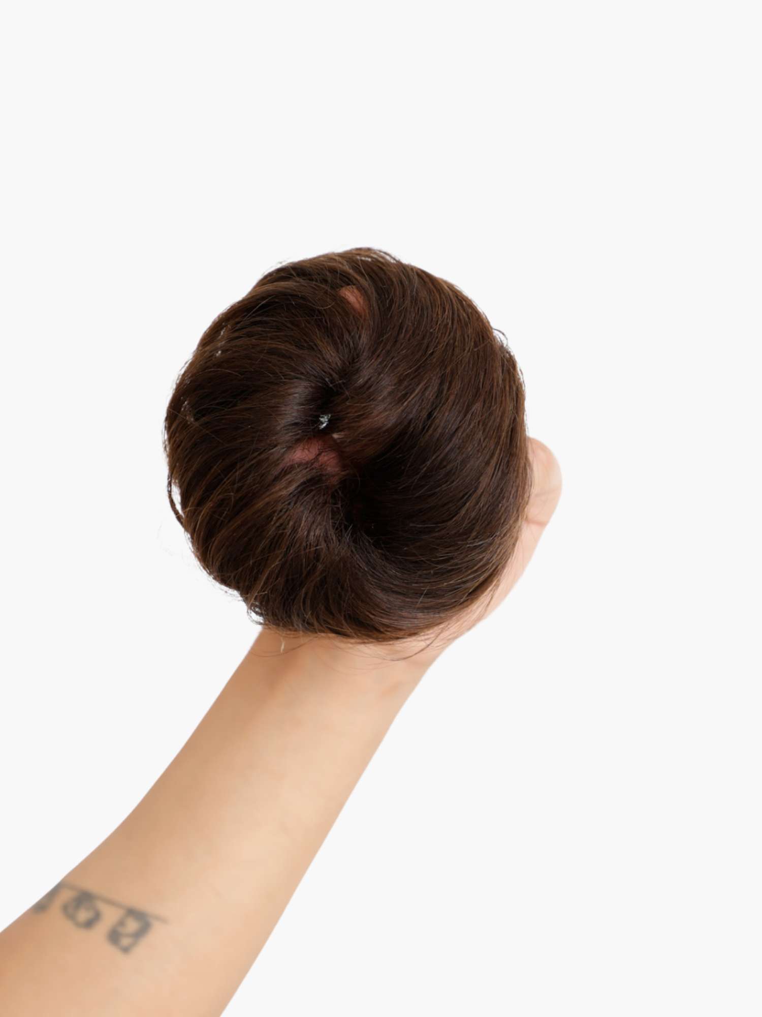 A hand holding a dark brown messy bun scrunchie.